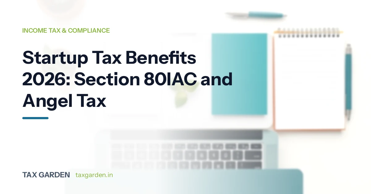 Startup tax benefits card on Section 80IAC and angel tax, with a laptop, notepad and pen on a desk